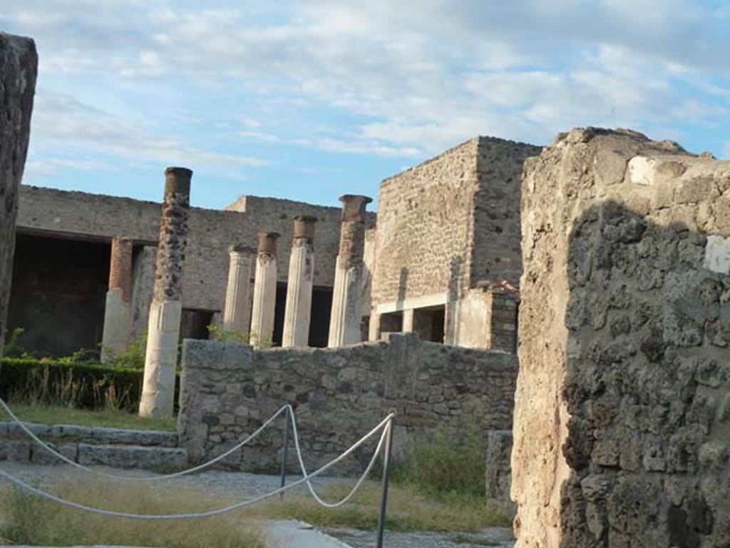 VII.7.5 Pompeii. September 2015. 
Looking across east side of atrium towards rooms (m), (n) and (o) on east side of peristyle and (q) and (r) in north-east corner.
According to Garcia y Garcia, this house had a beautiful marble impluvium in the centre of its atrium.
On the night of 24th August 1943, a bomb fell causing grave damage to this house.
It destroyed a part of the floor of the atrium and a good proportion of the rooms to the east and north-east of the peristyle.
Also destroyed was a part of the south and west of the portico, comprising of two columns with painted stucco.
The perimeter wall on the west, and three rooms on the north also fell, with the ruin of the best part of the painted fourth style plaster.
In the winter triclinium (n) on the east side of the peristyle, two important paintings that decorated it, were partially destroyed.
They were of Tryptolemus and the other of Venus, they have been restored in part. 
Tryptolemus was shown receiving the ears of corn from Proserpine.
Venus was shown arriving carried by a triton, with a cupid assisting her to descend to the shore.
A young woman was shown receiving her and making an offering upon a garlanded altar.
On the night of 13th September, this house linked to VII.7.2 was again hit by another bomb.
See Garcia y Garcia, L., 2006. Danni di guerra a Pompei. Rome: L’Erma di Bretschneider. (p.112-114 including photos)