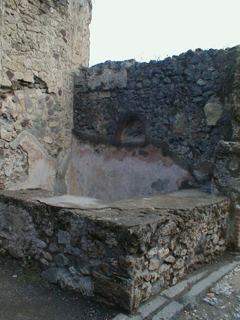 VII.7.11 Pompeii. September 2004. Two-sided sales counter, with niche for lararium in east wall. 
According to Boyce, the inside walls of the arched niche were coated with yellow stucco.
See Boyce G. K., 1937. Corpus of the Lararia of Pompeii. Rome: MAAR 14. (p.68, no.298)