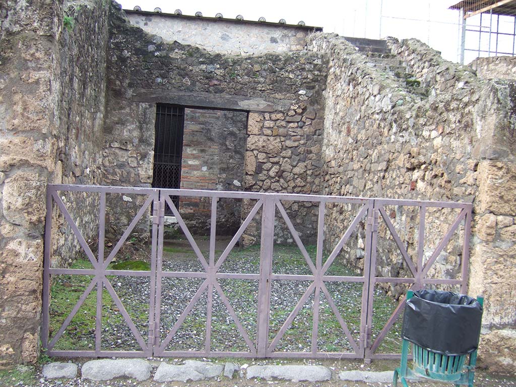 VII.7.30 Pompeii. December 2005. Shop/room next to steps next to VII.7.30, at the rear is the passageway to the posticum of the Temple of Apollo.
The reconstructed room with the iron gates at the rear was the area where the painting of Bacchus and Silenus was found.