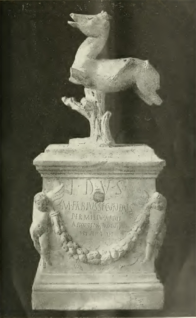 VII.7.32 Pompeii. Inscribed statue and base found 25th March 1817.
Now in Naples Archaeological Museum. Inventory number 3762.
Secondo Tarallo, trattasi di una basetta di marmo alta mm. 380, lunga mm. 340 e larga mm. 235. Nella parte anteriore, ai due angoli, sono rilevati due graziosi puttini o amorini che sostengono un festone di fiori e frutti. Tra la cornice superiore della basetta, ed il festone v'è incisa la seguente iscrizione:
T D V S
M FABIVS SECVNDVS
PERMISSV AEDIL
A HORDIONI PROCVLI
TI IVLI RVFI
Nella parte posteriore, ai due angoli, sono scolpiti a rilievo due uccelli, sulle due facce laterali pendono due altri festoni di foglie. Sormonta la basetta un quadrupede con le gambe stroncate, il quale è sorretto da un tronco d'albero. Sul dorso di esso si osservano i vesti di quattro zampe di un altro animale che gli è saltato addosso per dilaniarlo. Il tutto, compresa la base, è alto mm. 710. 
Parecchi studiosi presero ad esaminare il donarlo: ognuno manifestò la propria opinione; ma, poiché non si fu sempre di accordo nel determinare la divinità, a cui appartenesse il tempio, ove era stato rinvenuto, ne segni che non si fu sempre d'accordo nel determinare il nume, a cui quello fosse consacrato. Questa varietà d'opinioni proveniva dal fatto, che proprio il nome del nume era celato sotto le sigle T-D-V-S.
According to Tarallo, this is a marble base 380mm high, 340mm long and 235mm wide. In the front, at the two corners, there are two graceful cherubs or cupids holding up a festoon of flowers and fruit. 
Between the upper frame of the base and the festoon there is the following inscription: 
T D V S 
M FABIVS SECVNDVS 
PERMISSV AEDIL
A HORDIONI PROCVLI 
TI IVLI RVFI 
On the back, at the two corners, two birds are sculpted in relief, on the two side faces hang two other festoons of leaves. 
The base is surmounted by a quadruped with its legs missing, which is supported by a tree trunk.
On its back are the vestiges of four legs of another animal that jumped on it to tear it to pieces. 
The whole, including the base, is 710 mm high. 
Several scholars began to examine the donation: each expressed his opinion, but, since they were not always in agreement in determining the deity, to whom the temple belonged, where it was found, they were not always in agreement in determining the deity, to whom it was consecrated. This variety of opinions stemmed from the fact that the very name of the deity was hidden under the initials T-D-V-S.
Vedi/See Tarallo, E. Intorno al Donario del Pompeiano Marco Fabio Secondo in Rendiconti (Lincei) della Classe di scienze morali, storiche e filologiche, s5, v21, 1912, p. 69-78 and Tav. p. 78.