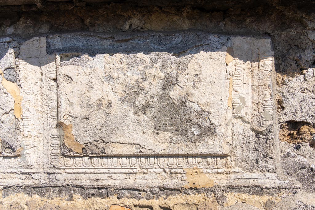 VII.7.32 Pompeii. October 2023. 
Detail of remaining decorative stucco from upper west wall of cella. Photo courtesy of Johannes Eber.