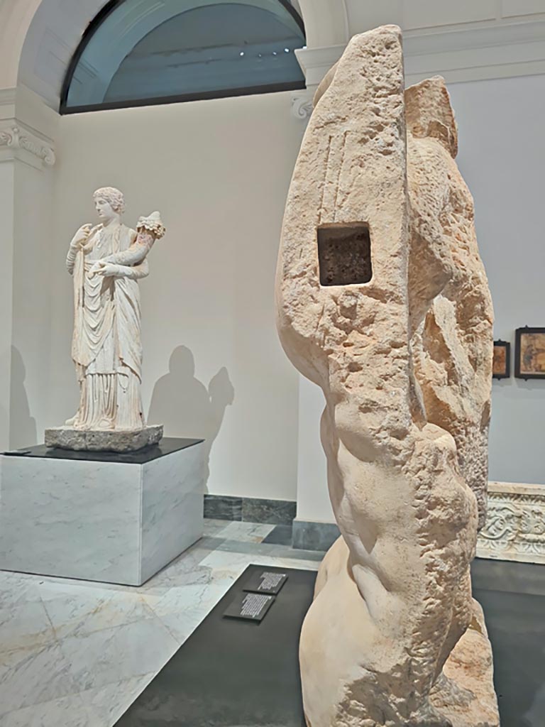 VII.8.1 Pompeii. April 2023. 
Detail of side and rear of block of white marble reworked to create the torso of a colossal statue of Jupiter.
The rear of the block has roughly carved depictions of a male figure (Dionysus?) and a boy
On display in “Campania Romana” gallery in Naples Archaeological Museum.  Photo courtesy of Giuseppe Ciaramella.