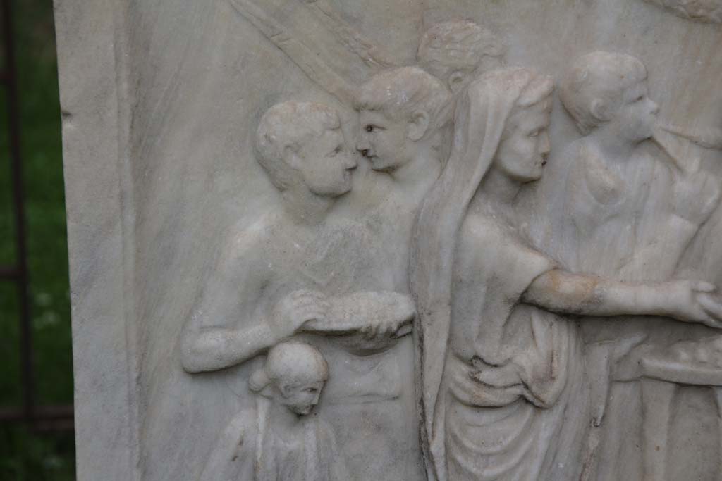 VII.9.2 Pompeii. April 2014. Detail from west side of Altar.  Photo courtesy of Klaus Heese.
According to Mau, this shows a priest with a toga drawn over his head pours a libation from a shallow bowl or patera onto an altar.
On the left are two lectors with their bundles of rods, a flute player, two boys – camilli - carrying the utensils for the sacrifice, and also an attendant.
See Mau, A., 1907, translated by Kelsey F. W. Pompeii: Its Life and Art. New York: Macmillan. (Pages 106-7).