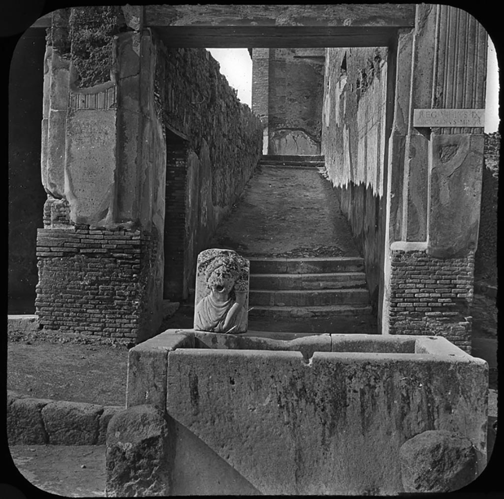 VII.9.67 Pompeii. 
Entrance doorway to stairs and ramp to upper level, at rear of fountain on Via dell’Abbondanza.
Photo by permission of the Institute of Archaeology, University of Oxford. File name instarchbx208im 027. Resource ID. 44353 
See photo on University of Oxford HEIR database