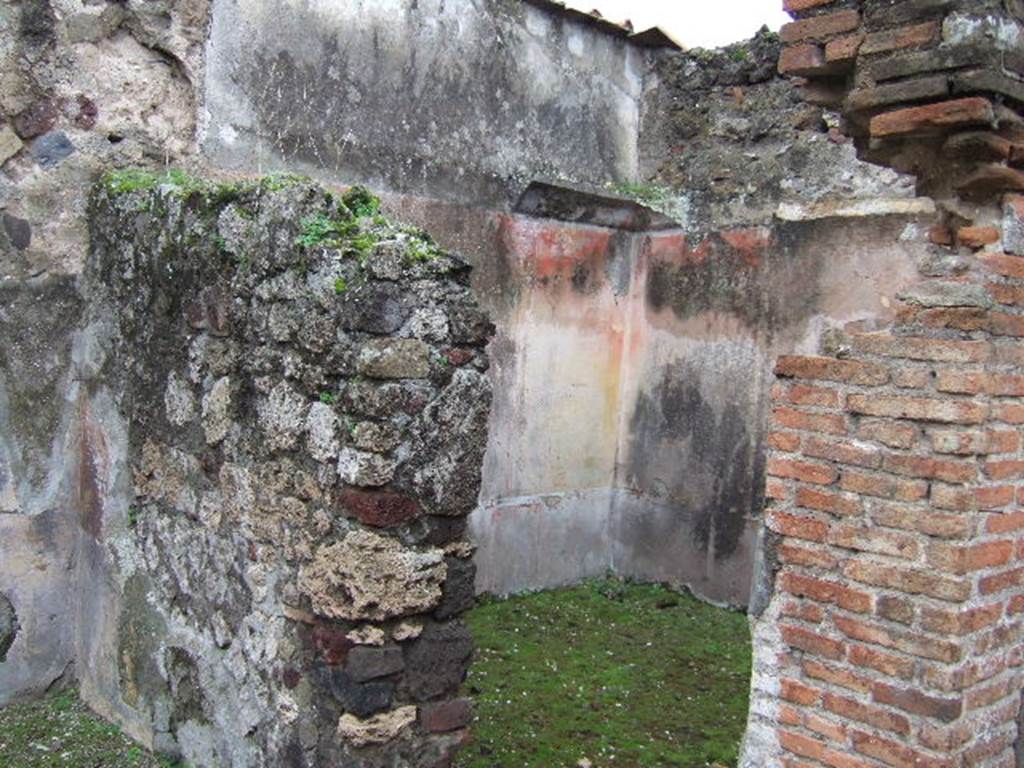 VII.10.3 Pompeii. December 2005. Doorway to room 12, on west side of atrium.
According to Amoroso, this may have been a cubiculum, or even a small oecus. (p.58)
The floor of this room was formed of mosaic, with white tesserae and probably a border of black tesserae.(p.74) The threshold was made from a square, formed by black mosaic lines between which was embedded a black diamond shape on a white background. The walls were renovated with IVth style paintings, the dark zoccolo showed red divisions, in which were painted plants.  The middle zone of each wall showed red and yellow vertical panels. 
In the central panel was a painting of the attributes of a divinity, the side panels showed pinakes with landscape paintings. The top of the walls had a white stucco cornice, preserved only in the south-west corner. The attributes of Diana, now faded and lost, were shown in a painting on the north wall, and objects sacred to Dionysius were painted on the west wall. 
Studi della Soprintendenza archeologica di Pompei, 22: l”Insula VII, 10 di Pompei , by Angelo Amoroso. (p.58 and p.74). 
According to Helbig, this room contained paintings of two chariots. 
See Helbig, W., 1868. Wandgemälde der vom Vesuv verschütteten Städte Campaniens. Leipzig: Breitkopf und Härtel. (246, 596)