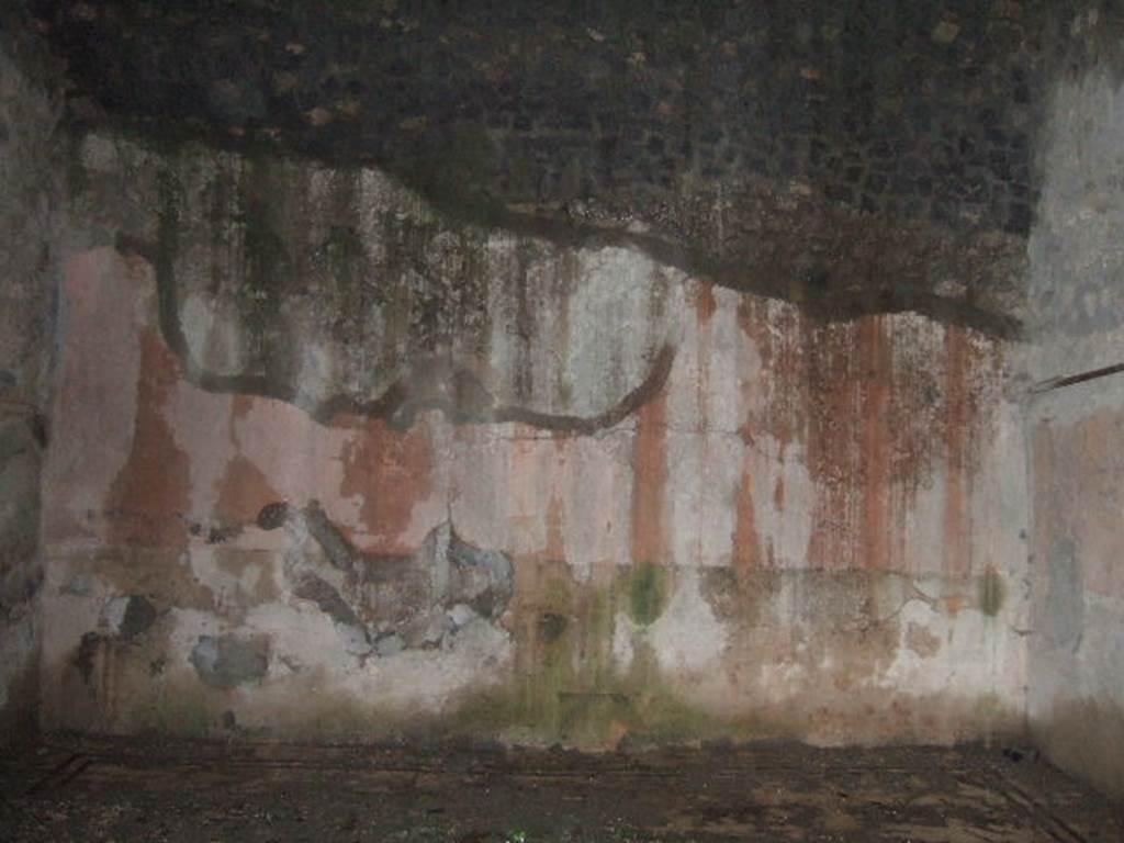 VII.10.3 Pompeii. December 2005. Room 14, east wall of exedra/oecus, at rear of peristyle garden. According to Fiorelli, two paintings were found in the exedra. One represented the head of Dionysus crowned with ivy leaves, with his head beside a Baccante appearing near his shoulder. The other was circular showing Perseus holding up the head of Medusa, to show the reflection in the water to Andromeda, who rests on his shoulder. On one side of the exedra are two other rooms, of which the second was used perhaps for a dormitory
See Pappalardo, U., 2001. La Descrizione di Pompei per Giuseppe Fiorelli (1875). Napoli: Massa Editore. (p.108)
According to Bragantini, the floor was black and white mosaic. In the centre was an emblema of opus sectile showing squares and triangles in coloured marbles. The walls were painted in the IVth style with a black zoccolo containing panels showing painted plants. The middle zone of the walls was red. On the south wall, in the centre of the black zoccolo was a yellow panel with painted plants. In the centre of the middle zone was a yellow panel with a painting, no longer recognisable.
See Bragantini, de Vos, Badoni, 1986. Pitture e Pavimenti di Pompei, Parte 3. Rome: ICCD. (p.177-8)
According to Richardson, found in the “triclinium” on the east side of the peristyle, were a painted bust of Bacchus and a maenad (Sommer negative 11918)
See Richardson, L., 2000. A Catalog of Identifiable Figure Painters of Ancient Pompeii, Herculaneum. Baltimore: John Hopkins. (p.127)
According to Helbig, found in the “triclinium” behind the peristyle was a painting of Perseus and Andromeda, (1198), and Bust of Dionysus, (385).
See Helbig, W., 1868. Wandgemälde der vom Vesuv verschütteten Städte Campaniens. Leipzig: Breitkopf und Härtel. (1198 and 385).
According to Amoroso, the exedra (our room 14) stood behind the viridarium and was decorated with a bacchic scene and with a pinax circolare in which were figured Perseus showing Andromeda the severed head of Medusa reflected in the water. 
Studi della Soprintendenza archeologica di Pompei, 22: l”Insula VII, 10 di Pompei, by Angelo Amoroso, (p.274)
