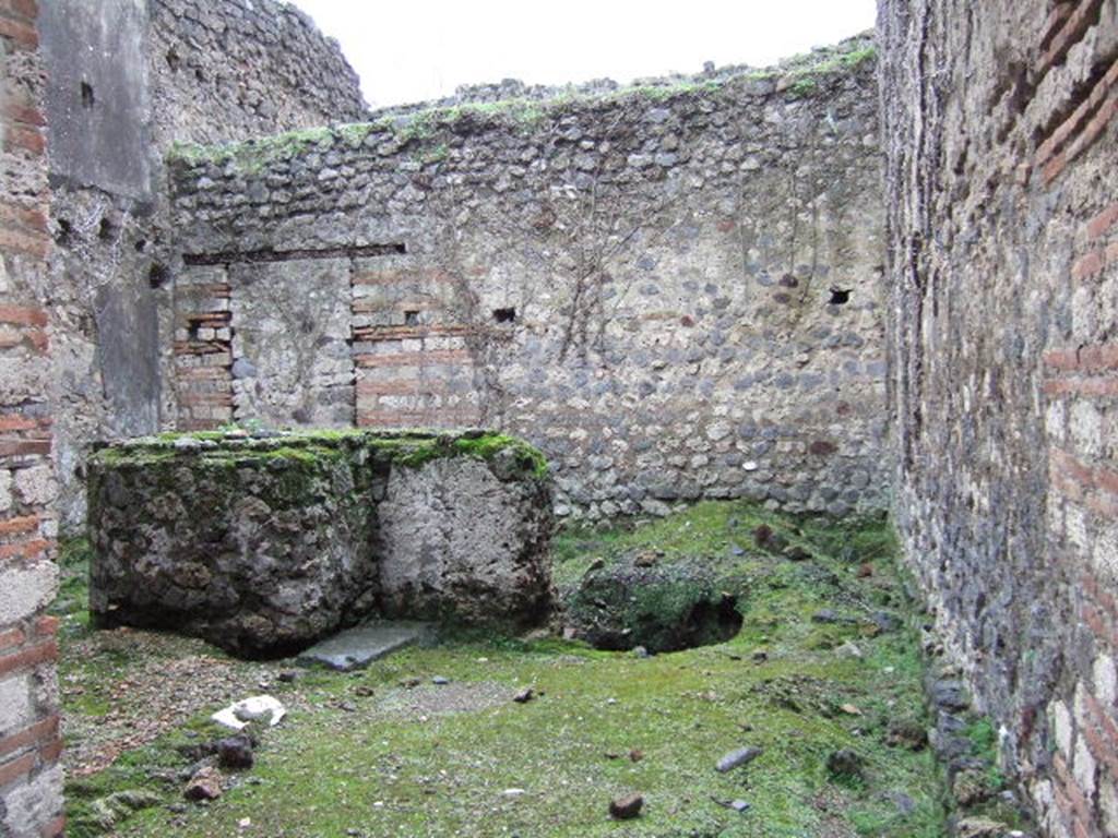 VII.11.7 Pompeii. December 2005. Looking south from entrance.
According to Liselotte Eschebach, this is a stable with livestock watering and feeding rack. 
To the right are holes for brackets, also large beam hole.
In the middle is a large round masonry vat or trough, next to it a well.
See Eschebach, L., 1993. Gebäudeverzeichnis und Stadtplan der antiken Stadt Pompeji. Köln: Böhlau, p. 323.
According to PPM, this was a Caupona, originally dependent on the house and communicating with it through a door in the rear room. 
The shop, in the centre, had a counter for serving wine, with an adjoining hearth.
See Carratelli, G. P., 1990-2003. Pompei: Pitture e Mosaici.  Roma: Istituto della enciclopedia italiana., VII, p. 453-5.