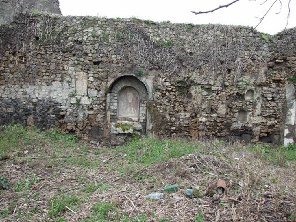 VII.11.14 Pompeii. March 2009. Garden “C”, west wall. According to Boyce, above a rectangular podium a projecting arch was built against the back wall, thus forming a niche. The front part of the upper surface of the podium served as an altar for sacrifices, on the front side of the podium was a step. On the rear wall of the niche are painted Jupiter and the Genius, with a blazing cylindrical altar between them. To the right and left on the wall outside the niche were the poorly preserved figures of the Lares. The side walls and the vaulted ceiling of the niche were decorated with leafy boughs. The exterior of the structure was coated with stucco painted in several different colours.
See Boyce G. K., 1937. Corpus of the Lararia of Pompeii. Rome: MAAR 14. (p.69, no.310 with Pl.14,1)