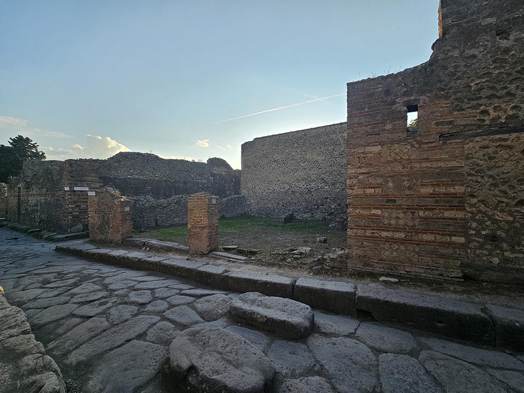 VII.11.17 and 16 Pompeii. November 2024. 
Looking south-west from Vicolo del Lupanare towards two shops at junction with Vicolo degli Scheletri, on left.
Photo courtesy of Annette Haug.