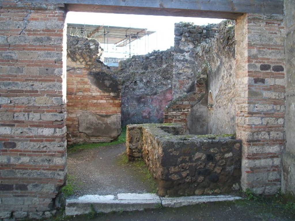 VII.12.15 Pompeii. December 2004. Entrance doorway and counter with hearth, and niche in west wall. At the rear is a doorway to a room used for the hospitality of the guests. See Della Corte, M., 1965.  Case ed Abitanti di Pompei. Napoli: Fausto Fiorentino. (p.202)