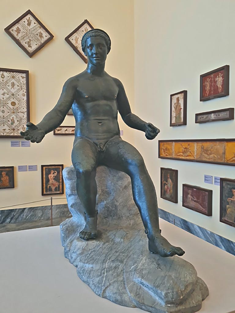 VII.12.23 Pompeii. October 2023. Bronze statue of Demetrios II. Photo courtesy of Giuseppe Ciaramella. 
On display in “L’altra MANN” exhibition, October 2023, at Naples Archaeological Museum, inv. 4892.
According to Jashemski, this was found against the west wall and was a statuette of Mercury, seated on a rock (inv. 4892).