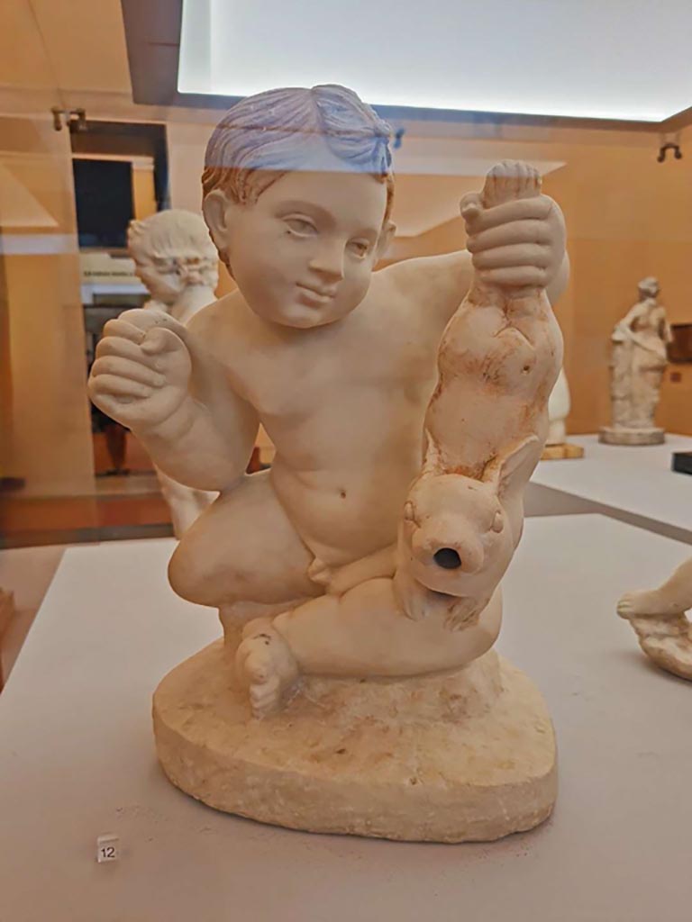 VII.12.23 Pompeii. October 2023. Marble statuette found in the garden area.
- (12) Fountain figure of a child holding up a hare, (inv. 6533).
Photo courtesy of Giuseppe Ciaramella. 
On display in “L’altra MANN” exhibition, October 2023, at Naples Archaeological Museum.