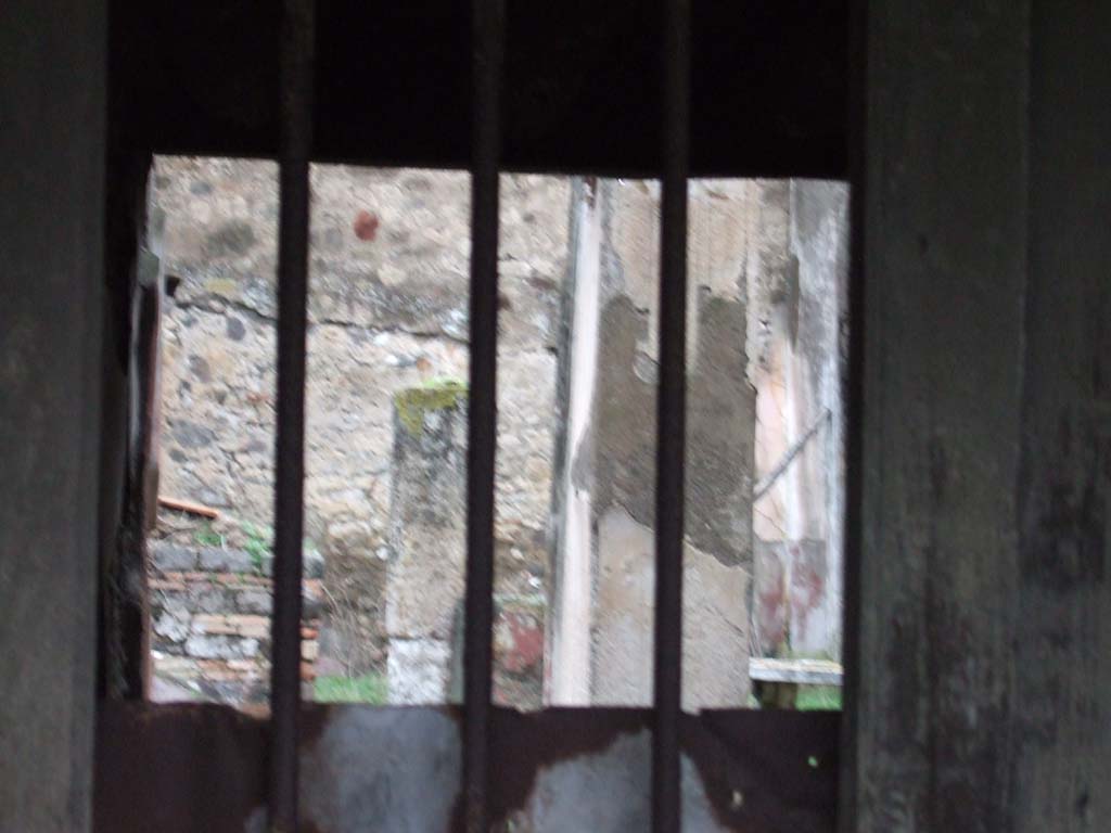 VII.12.28 Pompeii. December 2005. Looking north through doorway.
According to Pagano –
“Una scala di legno dava accesso al piano superiore, e questo slargavasi sulla via mediante un tavolato sorretto da travi e fornito di finestre che guardavano nella strada. Nel restaurarsi questo balcone, si era avuto mente a riprodurre con esattezza i legni che prima vi erando adoperati per sostenerio.
Entrando nella casa trovasi a sinistra la scalinata di legno che metteva al piano superiore. Viene in seguito un piccolo atrio dove ammirasi una graziosa fontana formata da un Puttino che regge colla sinistra una piccola colomba attualmente rotta, da cui sortiva un getto d’acqua che cadeva in una vaschetta. 
Al di sotto del tavolino che vedesi alle spalle del Puttino, si osservano quattro chiavi di bronzo, per somministrare l’acqua in diversi punti della casa.
Il tablino ha un quadretto sulla parete a sinistra, che esprime Alceste ed Admete, allegoria dell’amor coniugale.”
See Pagano, N. (1881).Guida di Pompei, ed.9. (p.49-50).
(translation –
"A wooden staircase gave access to the upper floor, and this opened up onto the street with a floor supported by beams and provided with windows looking into the street. In restoring this balcony, it had been thought to reproduce exactly the woods that had previously been used to support it.
Entering the house, on the left we find the wooden staircase to the upper floor. Then came a small atrium where one could admire a pretty fountain formed by a Puttino/small boy/cherub that held in his left hand, a small dove (or shell) currently broken, from which a jet of water would have fallen into a tub. 
Below the marble table we can see behind the Puttino, four bronze keys were observed, to administer water at different points of the house. 
The tablinum had a picture on the left wall, showing Alcestis and Admetus, an allegory of marital love.")
