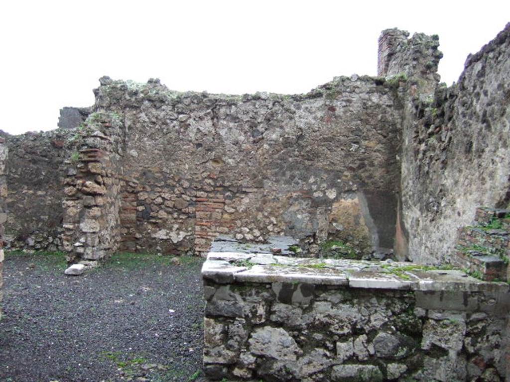 VII.13.24 Pompeii. December 2005. Looking east across two-sided counter, with hearth. On the left is a doorway into a side room.