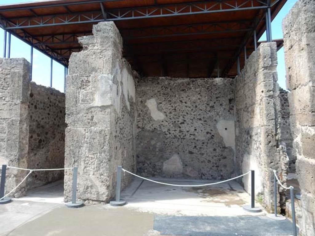 VII.15.2 Pompeii. May 2018.West side of atrium, with doorway to cubiculum, on left, and west ala, in centre. Photo courtesy of Buzz Ferebee. 
VII.15.2 Pompeii. May 2018.West side of atrium, with doorway to cubiculum, on left, and west ala, in centre.
Photo courtesy of Buzz Ferebee. 
According to Sogliano, seen in the west ala –
“A crowned cupid, and with green wings, playing the flute, leaning on a dolphin, throwing him into the sea.” (Evanescent)
(Eros coronato e con ali verde, suonante il flauto, appoggiato ad un delfino, che si precipita nel mare. (Evanescente)
(Bull.Inst, 1872, p.173, Fiorelli, Scavi di Pompei, p.124, no.199; Descr.Pomp, (p.305).
See Sogliano, A., 1879. Le pitture murali campane scoverte negli anni 1867-79. Napoli: Giannini. (p.62, no.355).
“Robust figure of a God, standing, turn to the left, and, apparently, naked: leaning with the left hand onto a trunk of a bare tree that forks into two branches, and in the right hand has something like a disc or globe, which you can not recognize with confidence.”
(Robusta figura di un Dio in piedi, volta a sinistra, e, a quel che pare, nuda: si appoggia con la sinistra a un tronco di albero sfrondato che si biforca in due rami, e nella destra ha come un disco o globo, che non si puo riconoscere con sicurezza.) (Bull.Inst, 1872, p.173) 
See Sogliano, A., 1879. Le pitture murali campane scoverte negli anni 1867-79. Napoli: Giannini. (p.127, no.619)
“Traces of female figure on foot, with a branch in her left hand.” 
(Tracce di figura muliebre in piedi con ramo (?) nel braccio sinistra.) 
(Bull.Inst, 1872, p.173)                                                          
See Sogliano, A., 1879. Le pitture murali campane scoverte negli anni 1867-79. Napoli: Giannini. (p.127, no.620)
According to PPM –
“In the centre of the west wall was located a female figure with a branch in her left hand, while in the north panel was a medallion with blue background”.
See Carratelli, G. P., 1990-2003. Pompei: Pitture e Mosaici: Vol. VII. Roma: Istituto della enciclopedia italiana, (p.730).