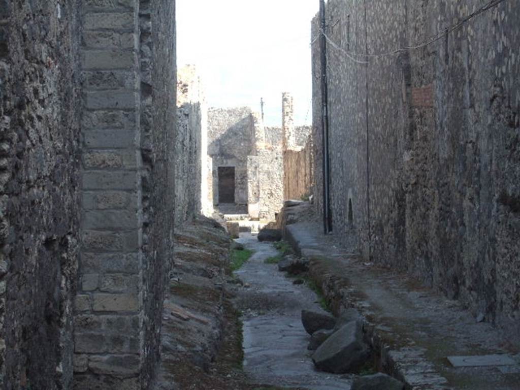 VII.6 Pompeii. September 2005. Vicolo del Farmacista, looking south.    VII.16 on right.  According to Garcia y Garcia, in 1943 the internal unexcavated area between VII.16. A and B (20 and 21) along the Vicolo del Farmacista was hit by a bomb. It fell on the soil not yet excavated and demolished the perimeter wall for a length of 4m x 3m and a part of the escarpment in two areas for 8 metres..
See Garcia y Garcia, L., 2006. Danni di guerra a Pompei. Rome: L’Erma di Bretschneider. (p.137)