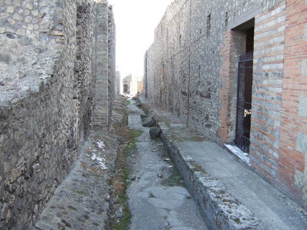 VII.6 Pompeii. September 2005. Vicolo del Farmacista, looking south. VII.16.21 on right. According to Garcia y Garcia, in 1943 the internal unexcavated area between VII.16. A and B (20 and 21) along the Vicolo del Farmacista was hit by a bomb. It fell on the soil not yet excavated and demolished the perimeter wall for a length of 4m x 3m and a part of the escarpment in two areas for 8 metres. 
See Garcia y Garcia, L., 2006. Danni di guerra a Pompei. Rome: L’Erma di Bretschneider. (p.137)