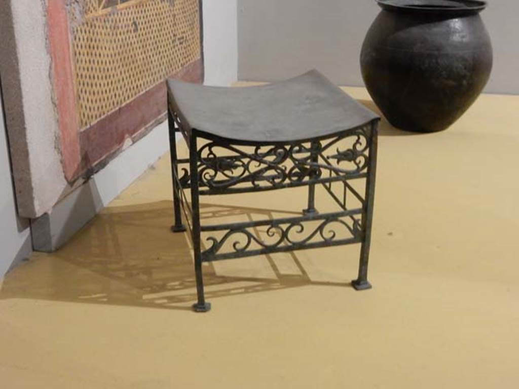 VII.16.17-22, Pompeii. May 2018. Bronze stool decorated with palms and lotus flowers. Parco Archeologico di Pompei, inventory number 13355.
Pot (olla) in bronze for the boiling of foods, Parco Archeologico di Pompei, inventory number 14069.  
Photo courtesy of Buzz Ferebee.