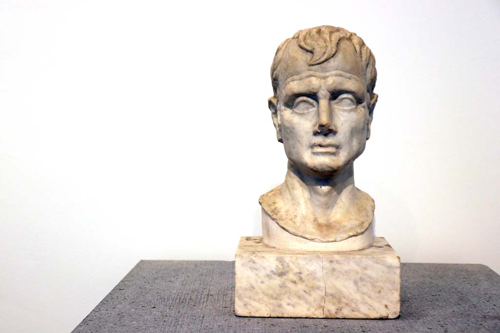 VIII.1.4 Pompeii. February 2021. Marble bust of a man, from VI.16.7. Photo courtesy of Fabien Bièvre-Perrin (CC BY-NC-SA).
According to Maiuri, (p.106 above) –
displayed in the Room of Livia and of Pompeian Portraits, were two heads found in the House of the Golden Cupids at VI.16.7. 
One being a portrait which was originally supported by a wooden herm, and the other an idealized head.