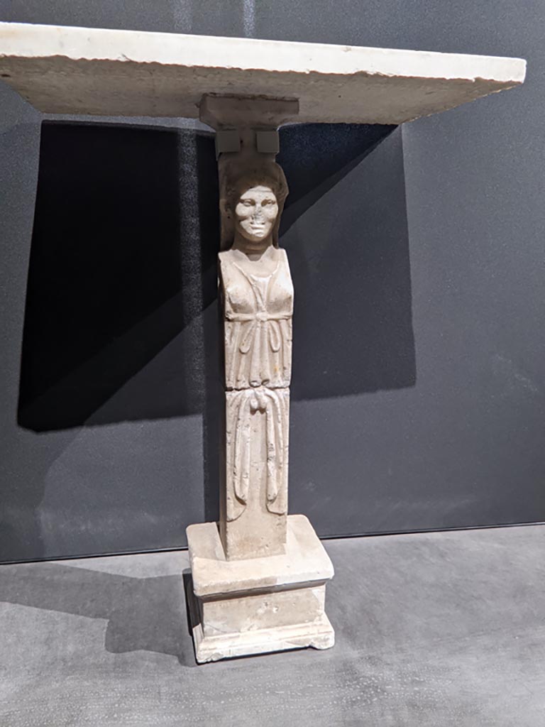 VIII.1.4 Pompeii. April 2022. 
Foot/leg of a table, on display in exhibition in the Palaestra. Photo courtesy of Giuseppe Ciaramella.
Could this be one of the monopodiums for supporting a table, as mentioned by Fiorelli, in either -
Fiorelli, G., 1897. Guida di Pompei, (p.110).
Fiorelli, G., 1877. Guida di Pompei. (p.108).
(for details of these pages, see VIII.1.4, part 5).