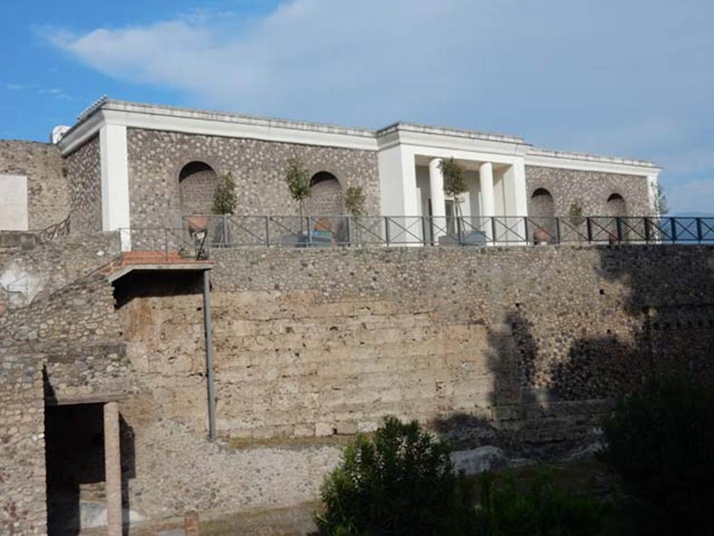 VIII.1.a Pompeii. May 2015. Looking east to north end of portico, remains of the city walls, and modern Antiquarium, above.  Photo courtesy of Buzz Ferebee.