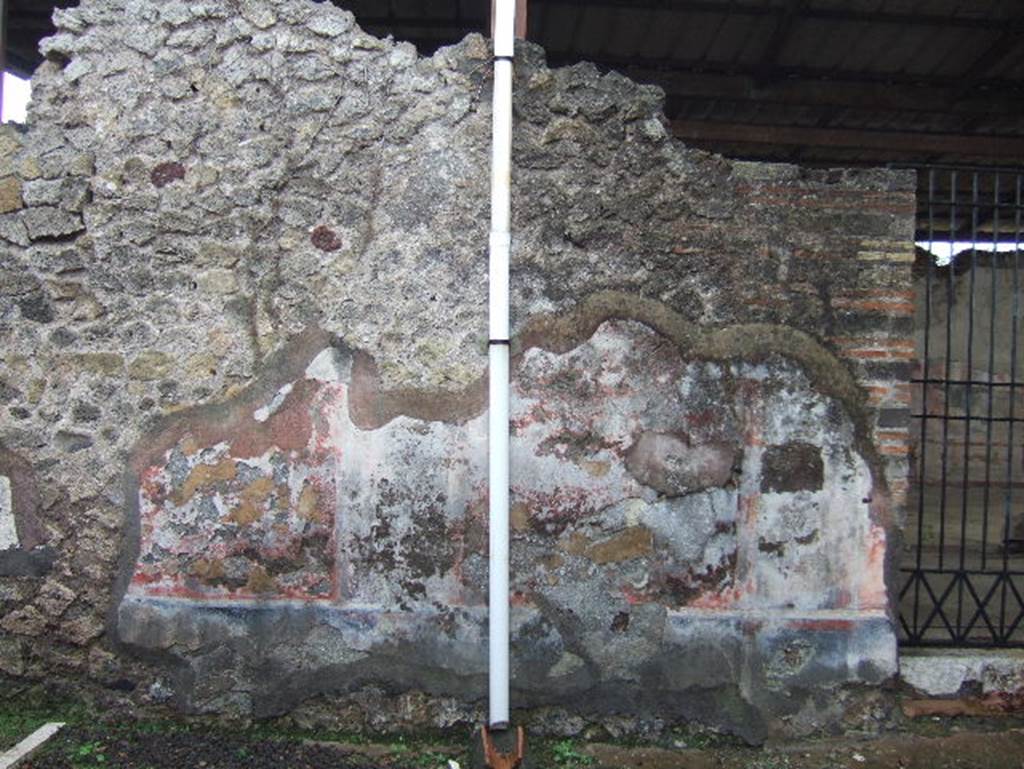 VIII.2.24 Pompeii. December 2005. South wall of bar, with doorway into palestra.
On the right, near the doorway, the black zoccolo (lower wall or dado) still retains the red border of one of its panels. The middle area of the wall would have had simple red panels separated by black compartments.