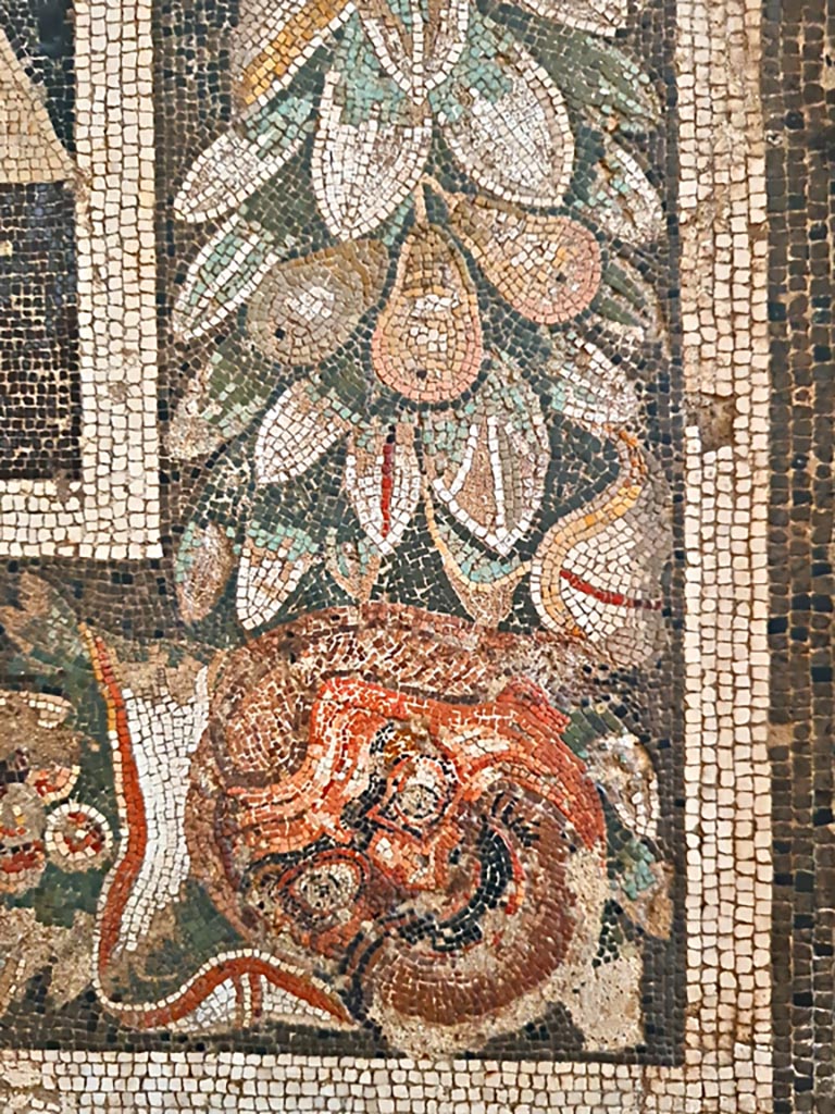 VIII.2.34 Pompeii. Detail of border-edge of mosaic showing mask, and garland with fruit. 
Now in Naples Archaeological Museum.  Inventory number 114281. Photo courtesy of Giuseppe Ciaramella. September 2024.