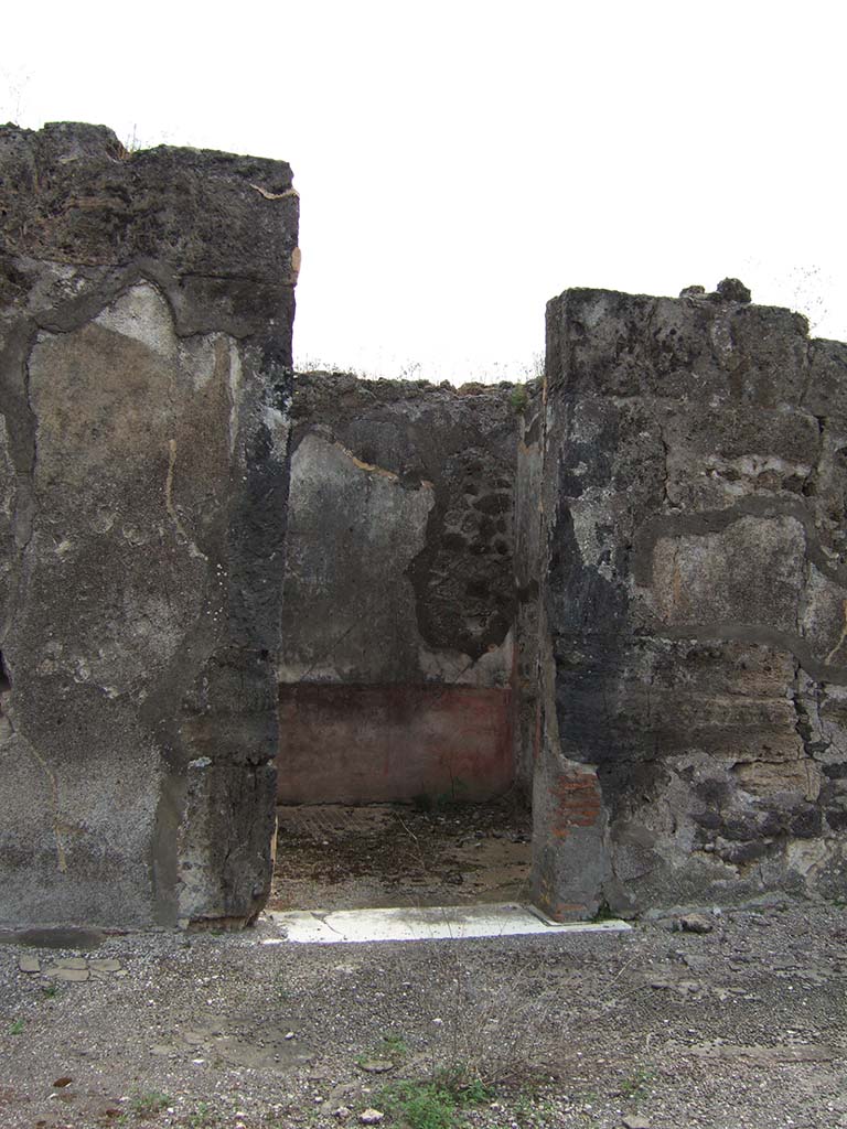 VIII.2.34 Pompeii. May 2006. Doorway to cubiculum ‘f’, in centre of east side of atrium.
The floor in this room was identical to room ‘e’, being of cocciopesto with dots of small white tesserae in regular lines.
The east wall can be seen through the doorway, with red zoccolo which had painted plants in panels separated from a central panel.
The middle zone of the wall would have been white.
