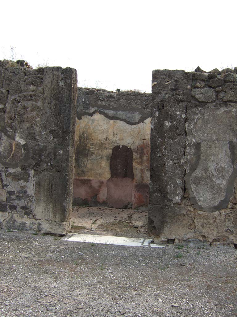 VIII.2.34 Pompeii. May 2006. Doorway to cubiculum ‘g’, on east side of atrium, next to east ala.
The threshold was of travertine with housing for the hinges of the door with two shutters opening towards the Interior of the room, like those of all the other rooms around the atrium. 
The walls were decorated with a red zoccolo partitioned into simple geometric panels.
In the middle of the walls, the red central panel was separated from the yellow side panels by a narrow white panel.
The upper zones of the walls were completely faded, but conserved a trace of a stucco cornice.
On the east wall, visible through the doorway, the large hole made by previous excavators or perhaps by burrowers after the eruption, can be seen.