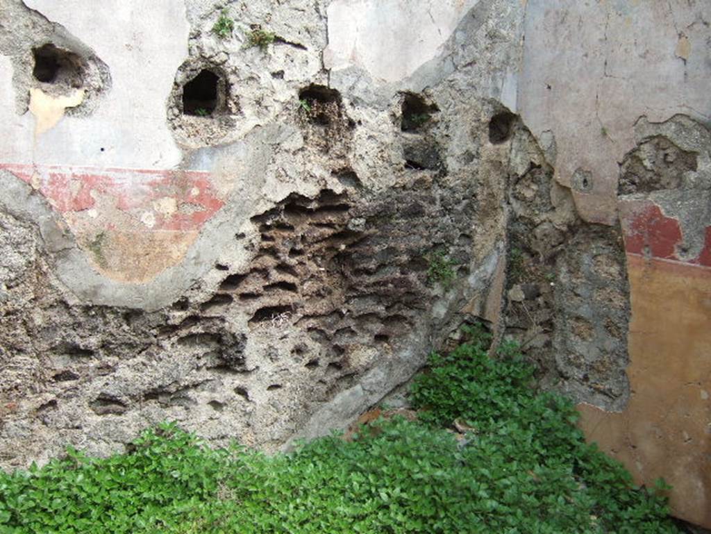 VIII.2.34 Pompeii. May 2006. Room ‘2’, north wall and north-east corner of another cubiculum. The yellow zoccolo reached the height 1.52m, before it was separated from the middle area of the wall by a painted red line. Above the red line the wall was painted black.
Inserted in the wall are the beam holes for the wooden floor supports of an upper mezzanine. The east wall, on the right, was the better preserved of the walls, and above the black painted area of wall, the upper part had been painted white.