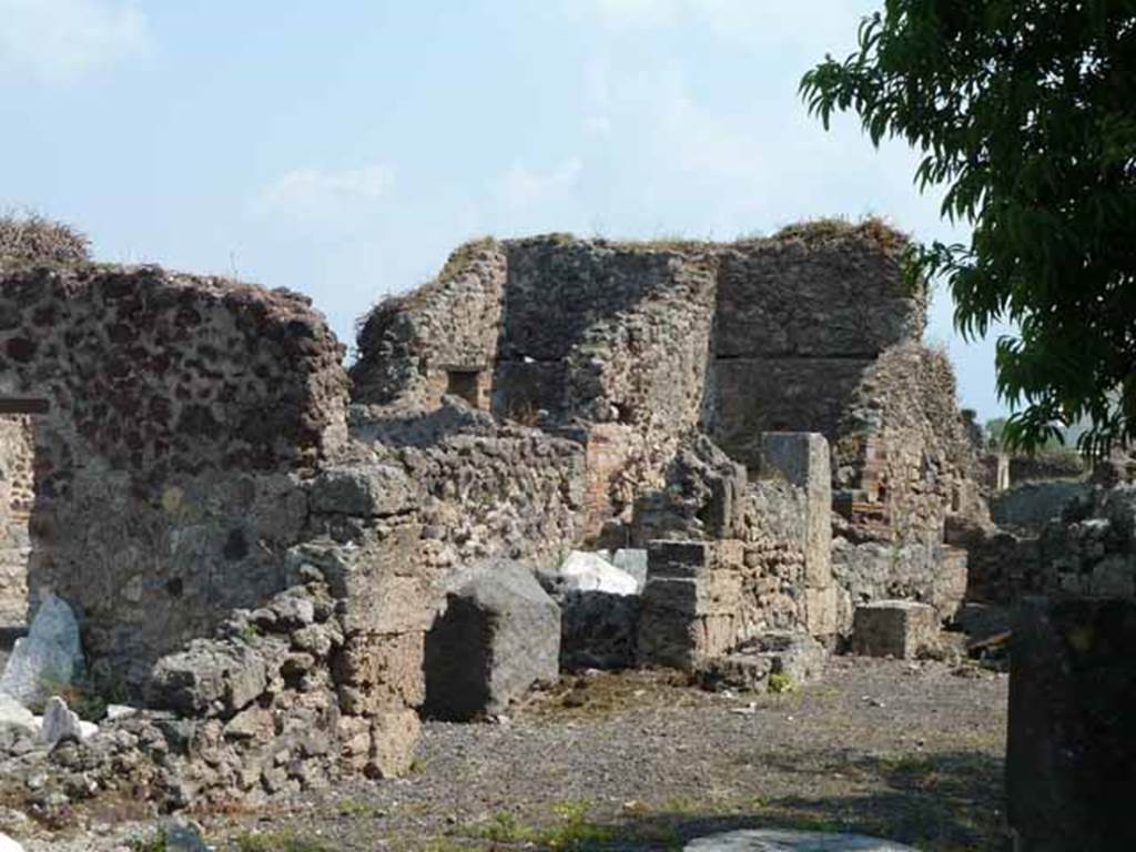 VIII.3.31 Pompeii. May 2010. Looking north-east across portico area towards rooms on the east side of the corridor. The high walls at the rear on the left centre, are the kitchen walls, the other high walls belong to a cubiculum. Taken across the wall of VIII.3.29.
