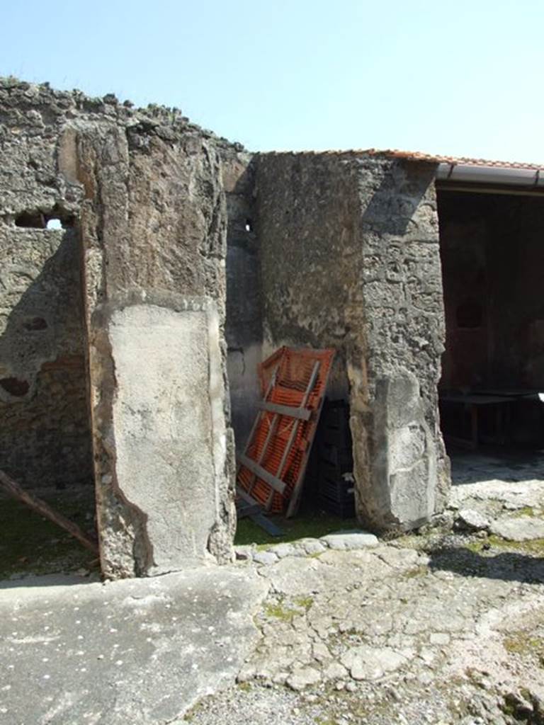 VIII.4.4 Pompeii. March 2009. Doorway to room 3.
According to PPM, the floor in this room was of lavapesto, whereas the atrium floor can be seen to include small tesserae of small white dots.
On the east side of the south wall of room 3, a medallion containing a griffin could be seen in the side panel, but hardly a trace is now left.
This room also had a Dionysian theme, similar to room 22, in that in the central panel of the white middle zone of the wall was a painting of a maenad and a satyr. 
On the west side of the south wall, with a faded zoccolo and a white middle zone, was a panel crossed by a candelabra and medallion containing a griffin. 
According to Fiorelli, “the threshold of the room was formed of Vesuvian stone, and the floor was of opus signinum with small pieces of marble encrusted into it for decoration.
The zoccolo of the walls were red and showed painted green plants, the middle zone was white divided into panels by small green lines and yellow ornaments: 
there were branches with leaves, and yellow candelabra topped with ornate globes, nearly similar to those from the cubiculum facing across the atrium.” (See room 22). 
See Pompei: Pitture e Mosaici, Vol. VIII parte 1, pp. 451ff.