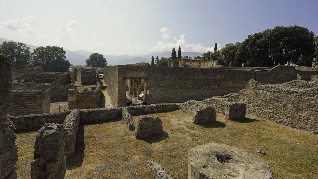 VIII.4.15 Pompeii. August 2021. Looking south from south portico onto lower level of VIII.4.27/29. Photo courtesy of Robert Hanson.
VIII.4.27’s rear entrance at VIII.4.29 is seen on the south side of peristyle, towards the right. 
Opposite, on the other side of Via del Tempio d’Iside, is the entrance to the Temple of Isis.