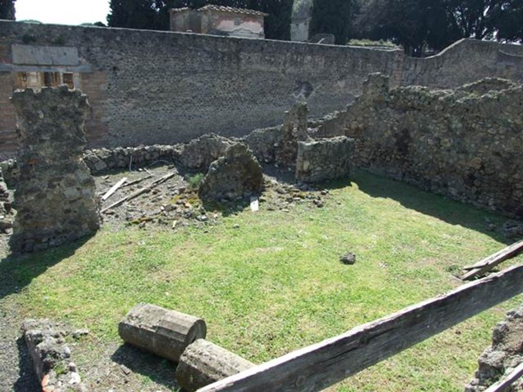 VIII.4.27 Pompeii. March 2009. Looking south from south portico of VIII.4.15, onto lower level. The remains of one of the four columns of VIII.4.15 (?) is lying on the grass, which would have been the peristyle area belonging to VIII.4.27. VIII.4.27’s rear entrance at VIII.4.29 is on the south side of peristyle.  According to Boyce, in this peristyle high up on the north wall was an arched niche.
See Boyce G. K., 1937. Corpus of the Lararia of Pompeii. Rome: MAAR 14. (p.76).
According to Jashemski, 
“The garden at the rear of the house had a portico on the east supported by two columns. 
There was an arched niche high up on the north wall. A passageway at the south-west corner at the rear of the garden led to the street, directly across from the Temple of Isis”.
See Jashemski, W. F., 1993. The Gardens of Pompeii, Volume II: Appendices. New York: Caratzas. (p.214).