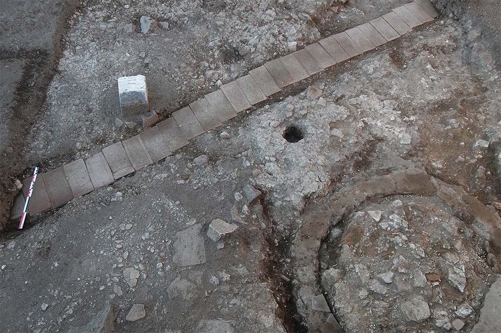 Fig. 17 – Pompéi, boulangerie VIII 4, 26-27 – Moitié méridionale de la salle des meules. 
L’alignement de briques correspond au passage d’un câble électrique ; au sud-est de la salle, la fosse septique avant le début du dégagement de son remplissage.
Pris du sud. Cliché : S. Zanella /EFR.