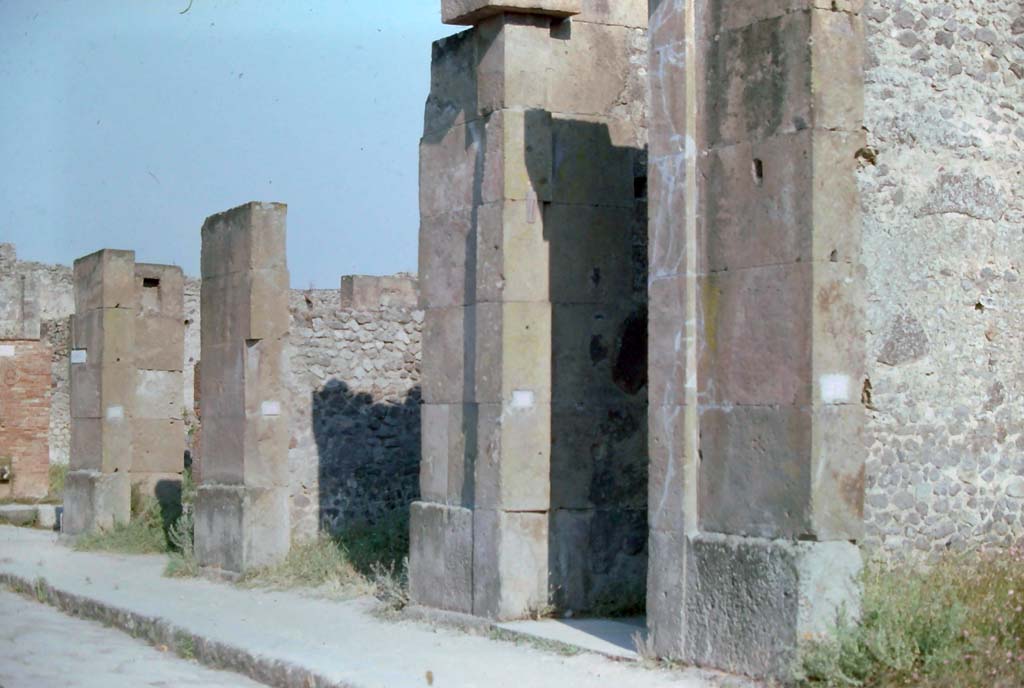 VIII.5.28 Pompeii. 7th August 1976. 
Looking south-east along south side of Via dell’Abbondanza, with Via dei Teatri, on left, followed by VIII.5.30/29/28 and 27, on right.
Photo courtesy of Rick Bauer, from Dr George Fay’s slides collection.
According to Bonucci, 
Casa di Fusco – 1819 - Before arriving to the Piazza del Teatro you pass by an infinite number of shops, which attest trade, and the riches of this city. Among them we can recognize, from their exhibition, those where the mosaicists worked. The fountains with beautiful quadrangular marble basins are abundant in this street. Their abundance, and that of wells, reservoirs, and cisterns, as well as the universal use of baths, public and private gardens, and galleries open to the sea attest to the great heat which suffer on this volcanic hill, and the well-understood measures taken to guarantee it. On this street a glass vase with whole eggs was found; and 939 bronze coins.
Fusco's house has a beautiful Gynaeceum, mosaics, and the varied and ingenious decorations in the capricious taste of a stage performer. Fish are depicted in the dining room, and love scenes in the bedroom. Not a few bronze, glass, and terracotta vases were found; two gold pendants, and a piece of pitch, which after so many centuries still retains the smell of that substance.
See Bonucci, C., 1827. Pompei Descritta: Terza Ed. Napoli: Miranda, p. 177.