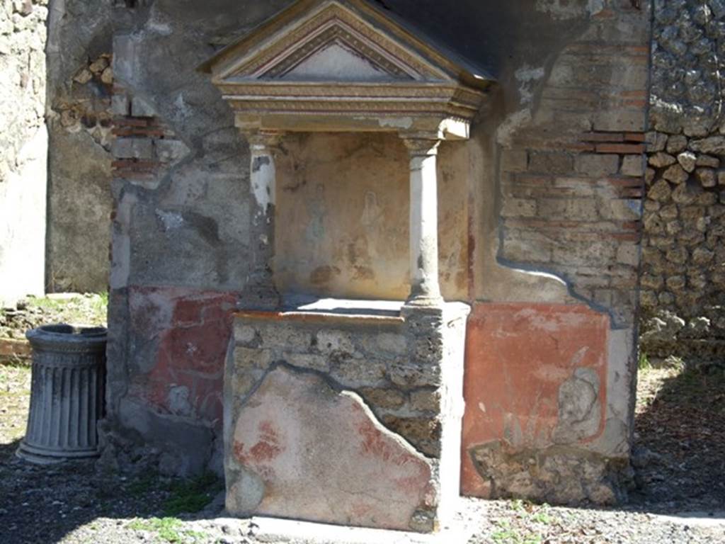 VIII.5.37 Pompeii. March 2009. Room 1, aedicula lararium in atrium.  
On the front of the podium was a painted round altar flanked by two serpents.  On the altar Two eggs and a pine cone were painted on the altar. See Fröhlich, T., 1991. Lararien und Fassadenbilder in den Vesuvstädten. Mainz: von Zabern. (L96, T: 8,3).
According to Boyce, this aedicula lararium had paintings and statuettes when found. The tympanum was white, bordered with a red stripe and painted on it were small gladiatorial arms. In the middle a helmet, to the left greaves, and to the right a shield and above it a dagger. Mau thought because of these paintings, the owner of the house may have been a retired gladiator. On the back wall within the aedicula was the lararium painting consisting of Genius and two Lares. When excavated, six bronze statuettes were found in this aedicula. They were of Aesculapius, Apollo, Mercury, Hercules and the two Lares. In addition to the statuettes, a bronze lamp with a crescent moon on its handle was also found.
See Boyce G. K., 1937. Corpus of the Lararia of Pompeii. Rome: MAAR 14. (p.77, no.371, and Pl.31, 1 and 2).