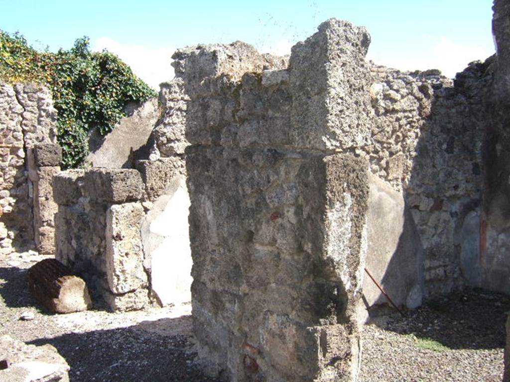 VIII.6.11 Pompeii. September 2005. Looking south-east towards rooms on south side of bakery. 
Doorway to room “c”, on the right. According to Mau, room “c” had simple decoration on a white background and a floor of opus signinum; a shelf was attached to the right wall and the rear wall. (“c” ha semplicissime pitture a fondo bianco e un pavimento di opus Signinum; al muro “d” e di fondo era attaccata una scansia.) 
Entrance corridor.
Doorway to room “b”, on the left. According to Mau, “b” was the panificium: against the east wall was a masonry foot of a large table: the other foot must have been made of wood.
In the rough-covered plastered walls one could see the holes for the supports of three shelves. The floor was made of opus signinum varied with white stones arranged irregularly
(“b” è il panificium; addosso al muro E sta un piede murato della grande tavola : l'altro piede dev'essere stato di legno. Nelle pareti, rivestite d'intonaco grezzo, si vedono i buchi dei mutuli per tre scansie. Il pavimento è formato di opus Sìgninum variato da pietruzze bianche disposte irregolarmente.)  See BdI, 1884, Page 138-9