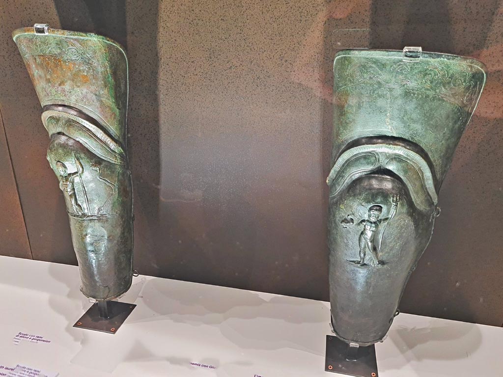 VIII.7.16 Pompeii. 
Pair of bronze leggings or Gladiator’s Greaves found in the barracks. 
On left - Bronze Greave with depiction of Jupiter, inv. 5645.
On right – Bronze Greave with depiction of Neptune, inv. 5647
Photo taken May 2021, courtesy of Giuseppe Ciaramella.