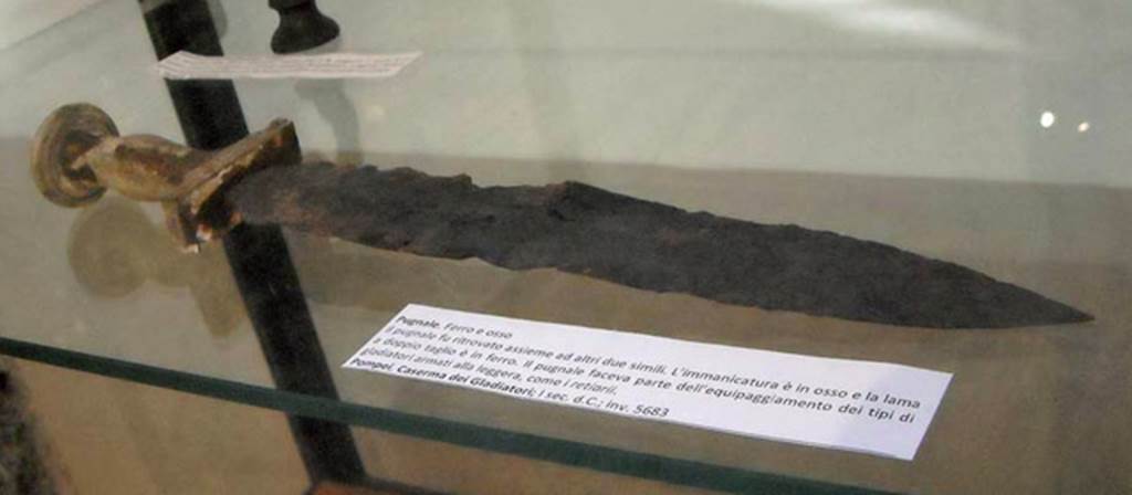 VIII.7.16 Pompeii. Gladiators dagger (pugnale) found in the Barracks with two other similar ones.
The handle is of bone and the blade is of iron and is double edged.
It was part of the equipment of a type of gladiator known as a retiarius (net fighter) who fought lightly armed. 
Now in Naples Archaeological Museum. Inventory number 5683.