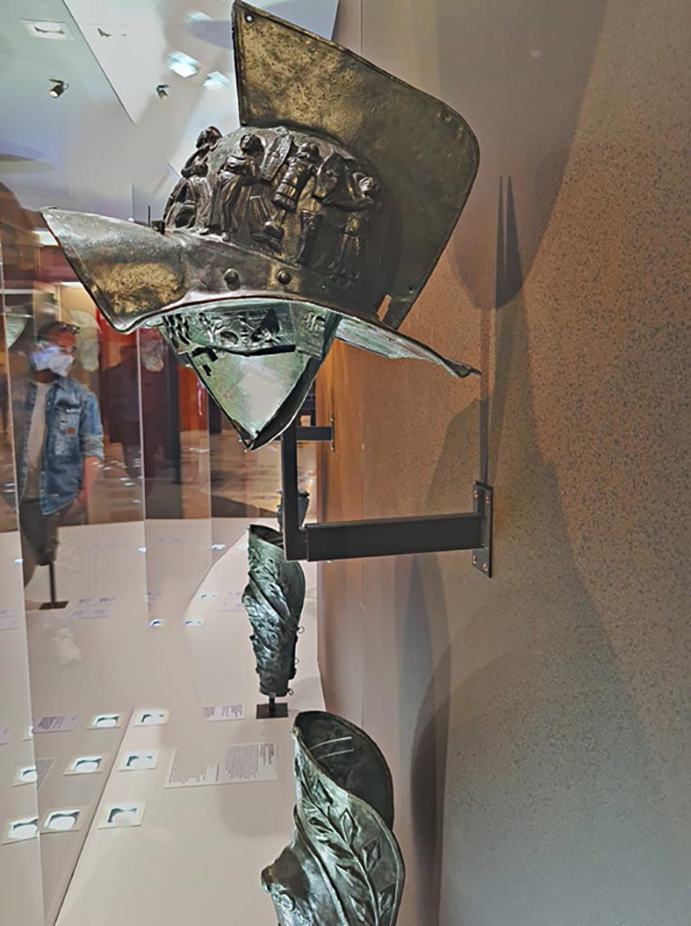 VIII.7.16 Pompeii. Photo taken May 2021, in Naples Archaeological Museum, inv. 5674.
Murmillo gladiator’s helmet, with personification of Rome, Barbarian captives, trophies and Victories, in display case. 
Photo courtesy of Giuseppe Ciaramella.