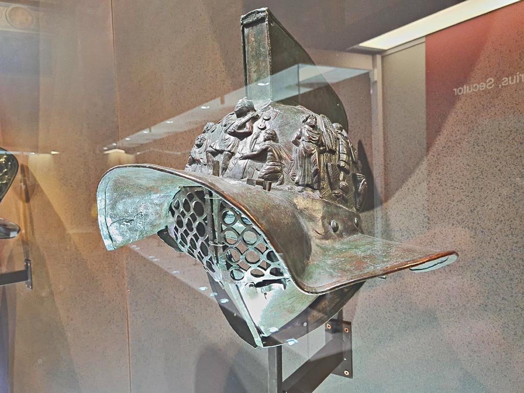 VIII.7.16 Pompeii. Photo taken May 2021, in Naples Archaeological Museum, inv. 5674.
Murmillo gladiator’s helmet, with personification of Rome, Barbarian captives, trophies and Victories. 
(Side 1). Photo courtesy of Giuseppe Ciaramella.