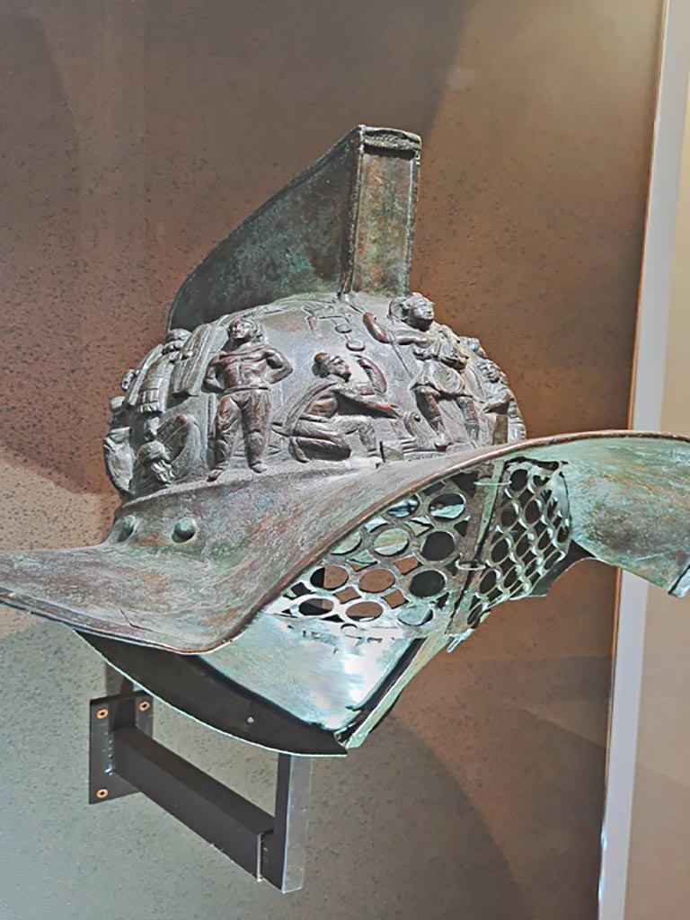 VIII.7.16 Pompeii. Photo taken May 2021, in Naples Archaeological Museum, inv. 5674.
Murmillo gladiator’s helmet, with personification of Rome, Barbarian captives, trophies and Victories. 
(Side 2). Photo courtesy of Giuseppe Ciaramella.