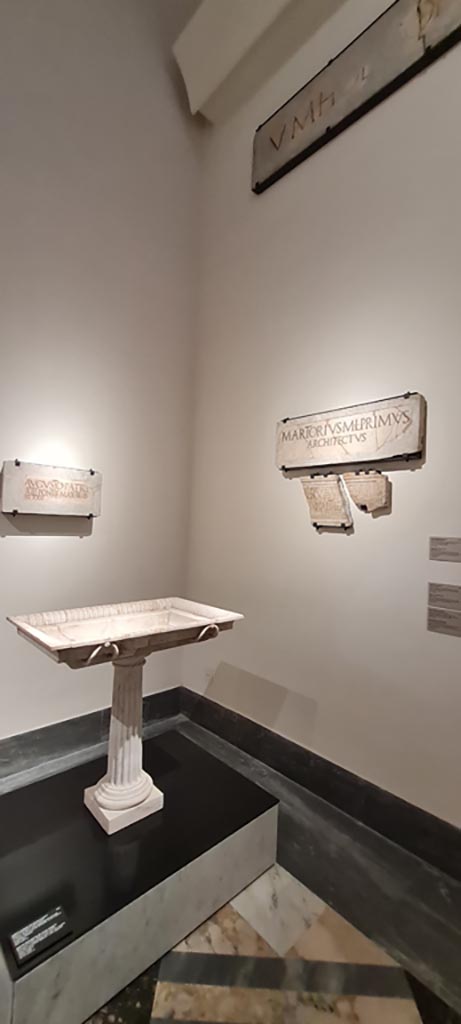VIII.7.20 Pompeii. April 2023. 
White marble basin of a fountain (inv. 6868) on display in “Campania Romana” gallery in Naples Archaeological Museum.
On left, Dedication to Augustus, 
On right, marble slabs ((inv. 3834 and 3823).