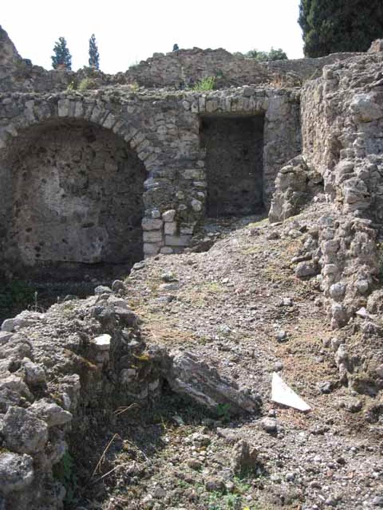 VIII.7.22 Pompeii. September 2010. Looking west from kitchen area of VIII.7.23, into corridor area of VIII.7.22. Photo courtesy of Drew Baker.
The area on the right side of the picture would seem to be the area of the lararium which would have been on the north wall of the corridor, see below. Although Boyce described the lararium as being in an arched niche, his measurements would make the one in the picture above, on the west wall and too big. According to Boyce, in the north wall of a corridor leading from the underground kitchen to the posticum of VIII.7.22, was a large arched niche. This was I.0 metre high, 0.85 wide, 0.50 deep and 0.70 above the floor. The back wall of the niche was painted red, and on it was the figure of Fortuna, clad in a green tunic and yellow mantle. In her left hand she held a cornucopia, and in her right, a rudder. To the left of her feet was a large globe.
The side walls of the niche and the area under the feet of the goddess were decorated with green plants.
See Boyce G. K., 1937. Corpus of the Lararia of Pompeii. Rome: MAAR 14.  (p.78, no:378)
Fiorelli describes, VIII.7.22 as a corridor belonging to VIII.7.24, with stairs to upper floor.  Nearby is the kitchen, in which remains the niche of the Penates, with the image of Fortuna with cornucopia and rudder.
See Pappalardo, U., 2001. La Descrizione di Pompei per Giuseppe Fiorelli (1875). Napoli: Massa Editore. (p.134)
