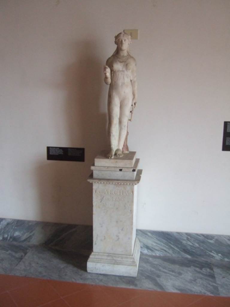 VIII.7.28 Pompeii.  Marble statue of Isis holding a sistrum in her right hand (now missing) and key of the Ankh (the key of life or the Nile) in her left.  
The key was originally gilded and coloured.  The pilaster on which the key leans has the inscription of the freedman L Cecilio Febo.  Found in the north east corner of the portico.  Now in Naples Archaeological Museum. Inventory number 9976.