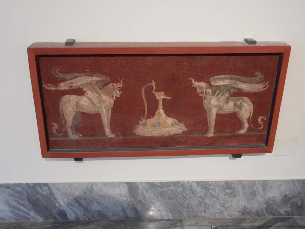 VIII.7.28 Pompeii. June 2019. Painted panel found in the zoccolo of the centre of the south wall in the Ekklesiasterion. 
A jug is between two winged androsphinxes. Photo courtesy of Buzz Ferebee.
Now in Naples Archaeological Museum. Inventory number 8563.