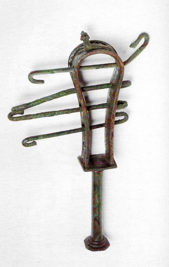 VIII.7.28 Pompeii. The instrument was found on January 4th, 1766 in the Ekklesiasterion.
The sistrum is adorned on the top with a crouched cat and on the sides with lotus flowers. 
It was found together with some marble fragments of limbs, among which some of the hand that originally held it and of a marble head of Isis.
Now in Naples Archaeological Museum. Inventory number 2397.