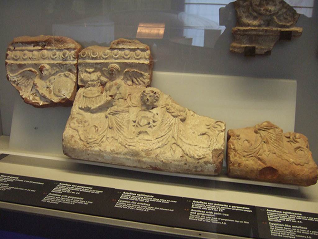 VIII.7.28 Pompeii. Temple pediment façade.  
Moulded relief with two winged figures facing each other, one holding a shield and the other holding armour. 
Vines fill the gaps below and a Dionysian head is superimposed. Now in Naples Archaeological Museum.  Inventory numbers 21473, 21482, 21483.