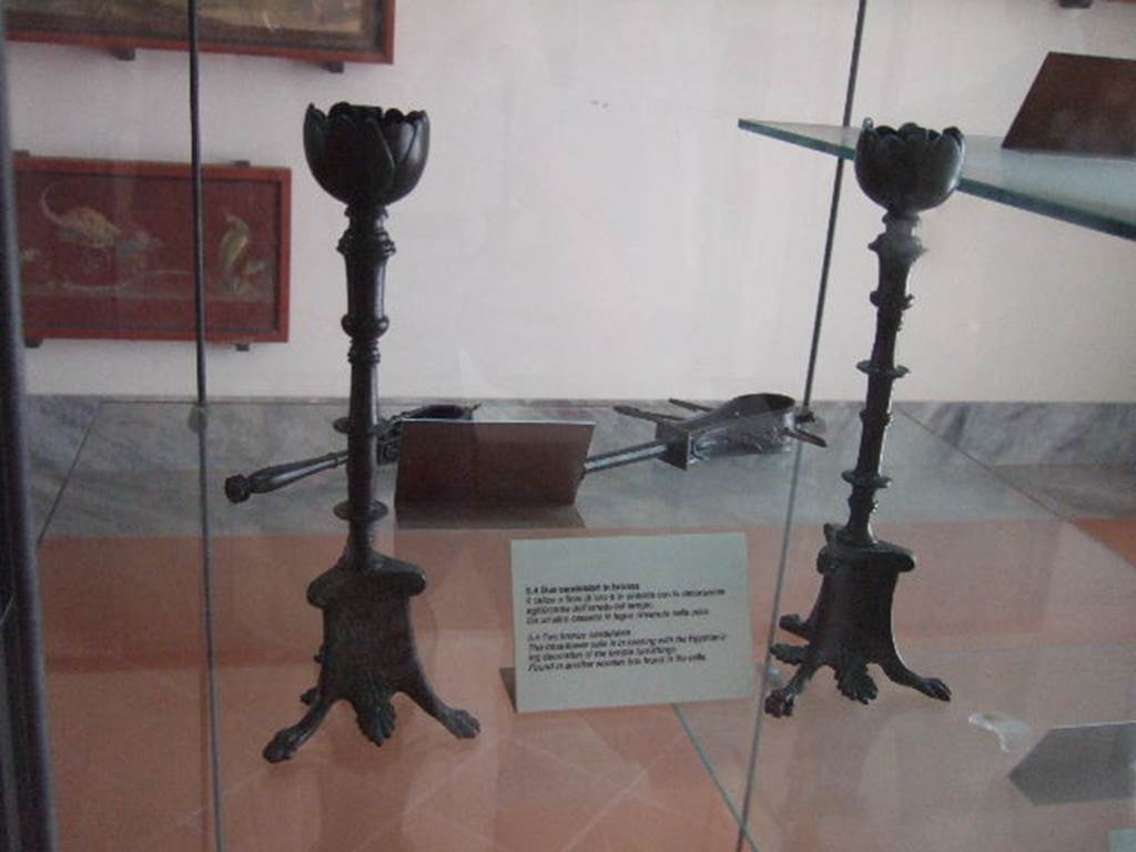 VIII.7.28 Pompeii. Found in another wooden box in the temple cella. Two similar but not identical bronze candelabra. 
The tops are lotus flowers and the feet have lion’s paws with palm leaves between. The decoration of the stems differs on each.
Now in Naples Archaeological Museum. Inventory numbers 72192 and 72193.